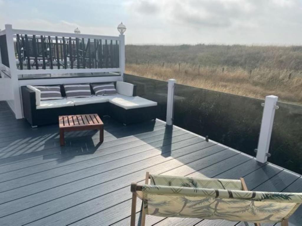 a deck with a couch and a table and a bench at Riverside terrace - Overlooking the nature reserve in Rye Harbour