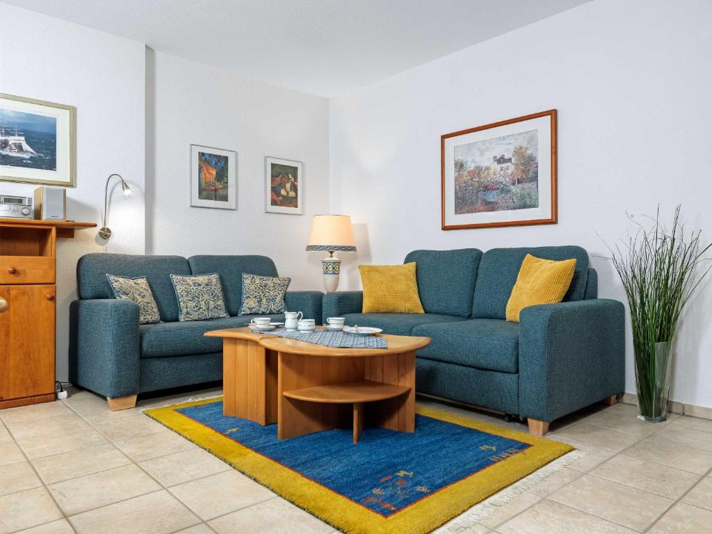 uma sala de estar com dois sofás azuis e uma mesa de centro em Ferienwohnungen Fischerstieg Pier 17 em Timmendorf
