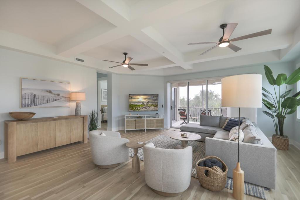 a living room with a couch and chairs and a tv at Ibis At The Sanctuary A302 in Sanibel
