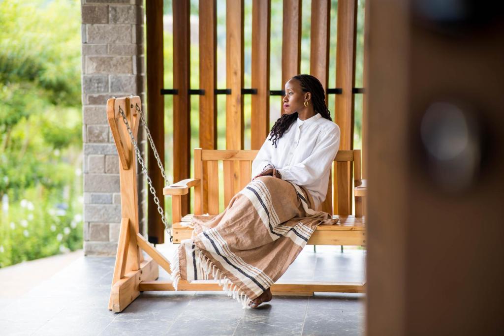 Una donna seduta su una panchina in veranda di Tabebuia Spa and Safari Resort a Fort Portal