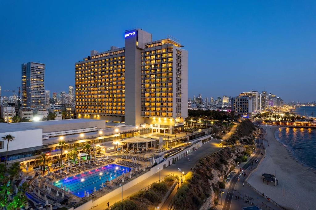 a large building with lights in a city at night at Hilton Tel Aviv Hotel in Tel Aviv