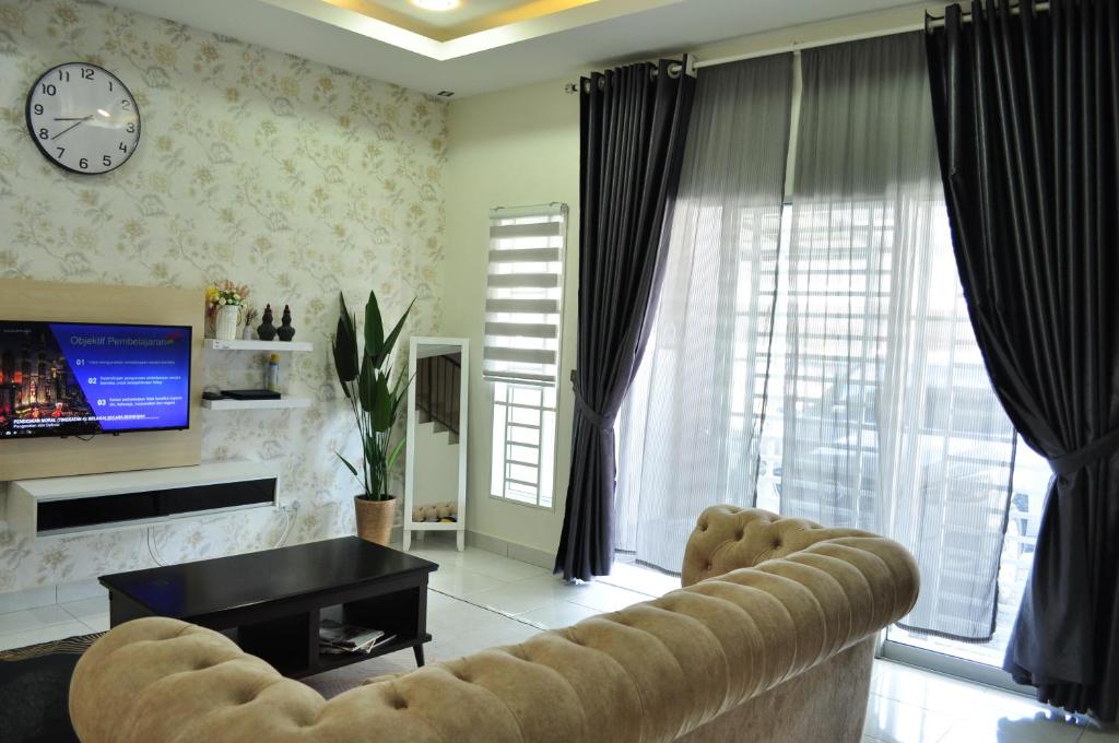 a living room with a couch and a clock on the wall at De’ Nuhir Homestay Teluk Senangin in Kampong Batu Tiga