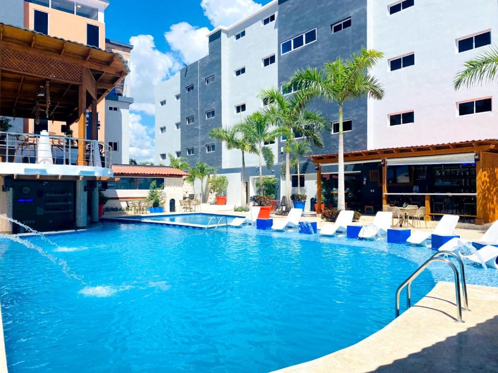 a swimming pool in a hotel with chairs and buildings at Halibut Hotel in La Romana