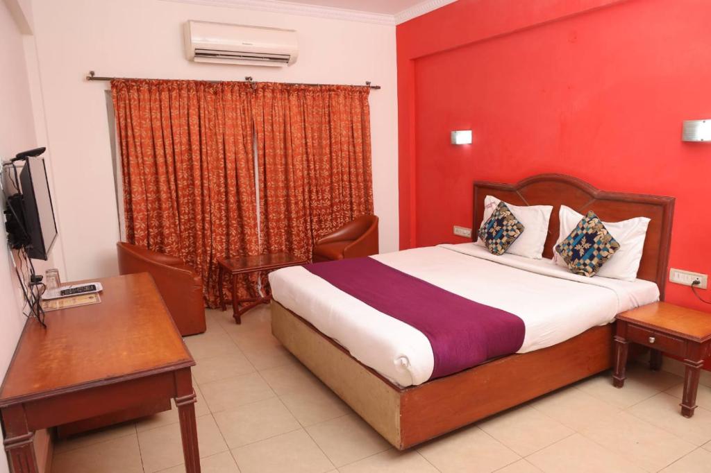 a bedroom with a bed and a desk and a television at GOLDMINE HOTELS in Chennai