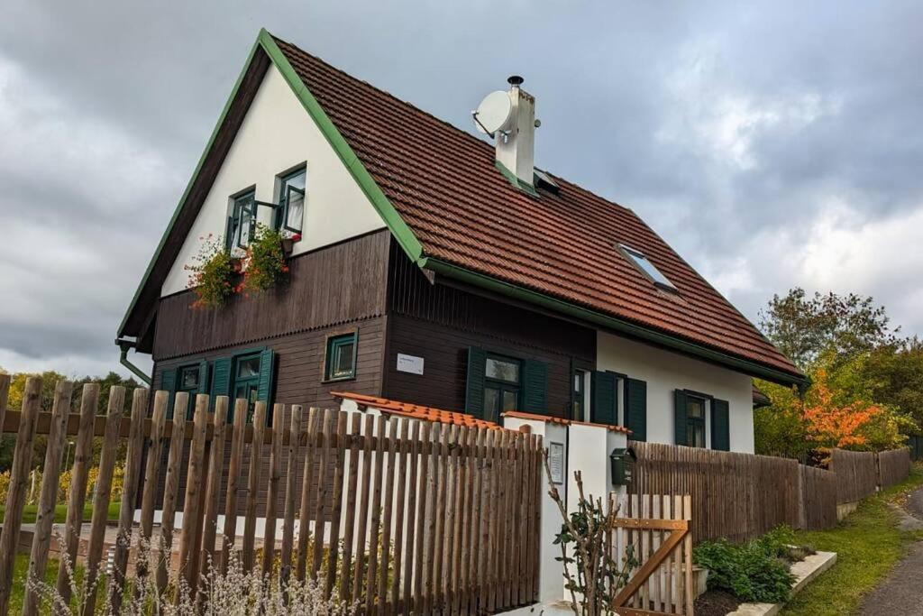 una casa marrone e bianca con una recinzione in legno di Cozy cottage Geltschberg Nr. 1 a Liběšice