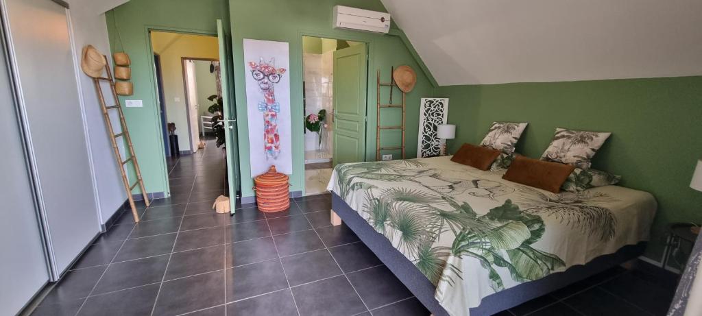 1 dormitorio con cama y pared verde en Appartement Corail, situé à 2 min du lagon, en Saint-Leu