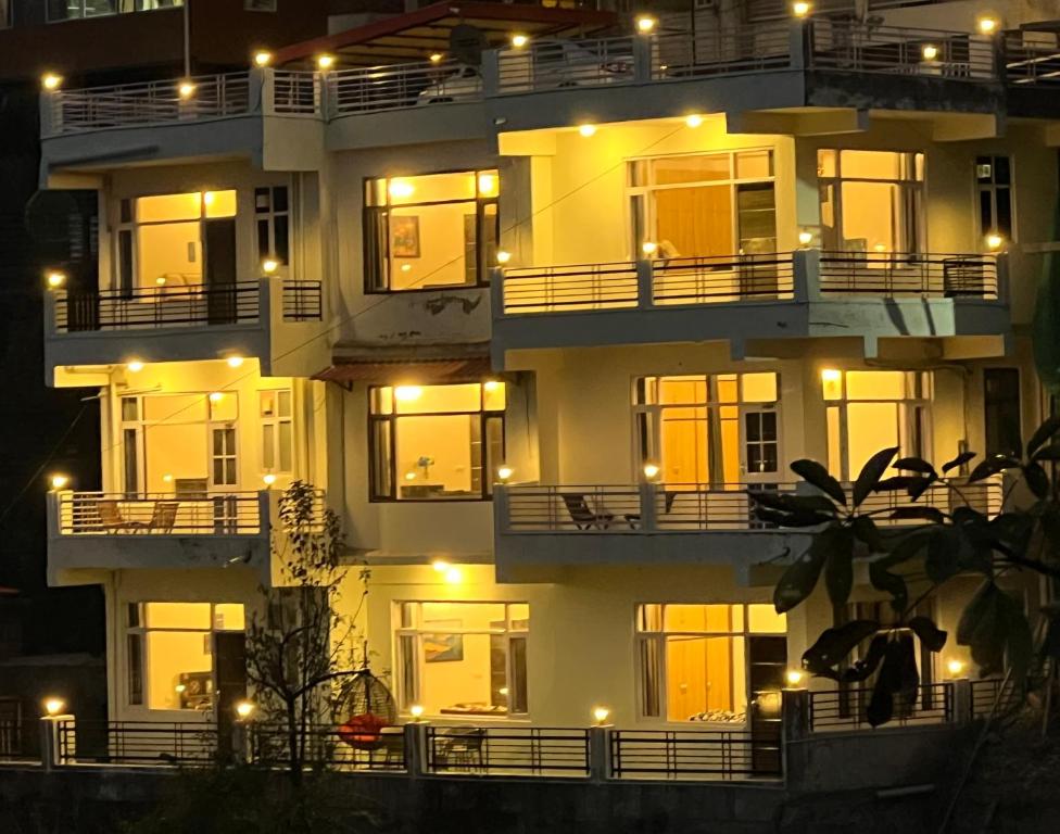 un gran edificio de apartamentos con ventanas iluminadas por la noche en Myst Asthetic Stays, en Kasauli