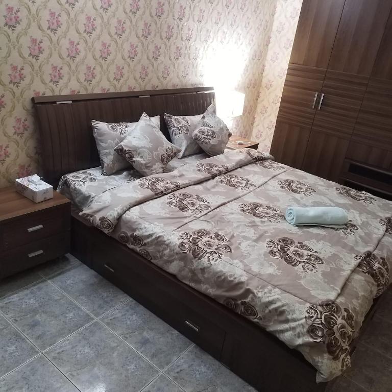 1 dormitorio con cama con cabecero de madera y almohadas en العين الهيلي مصباح ب 6, en Al Ain