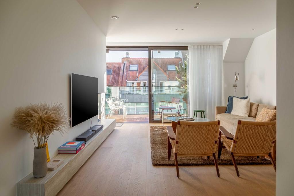 a living room with a television and a table and chairs at Stunning duplex - 3 bedroom - 2 sunny terrasses in Knokke-Heist