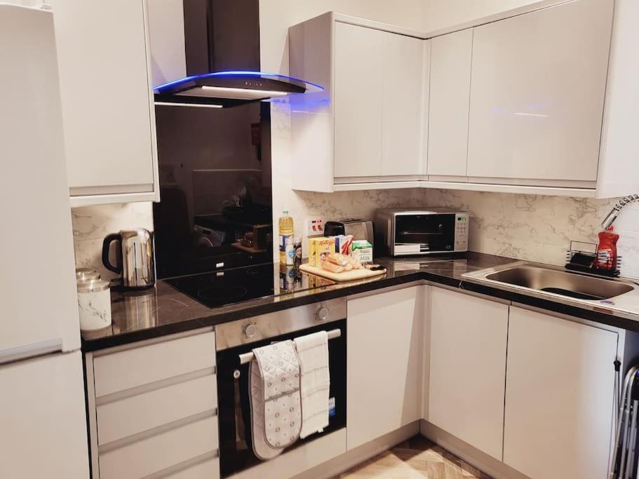 uma cozinha branca com armários brancos e um lavatório em High Street, 2 bed, newly refurb em Leamington Spa