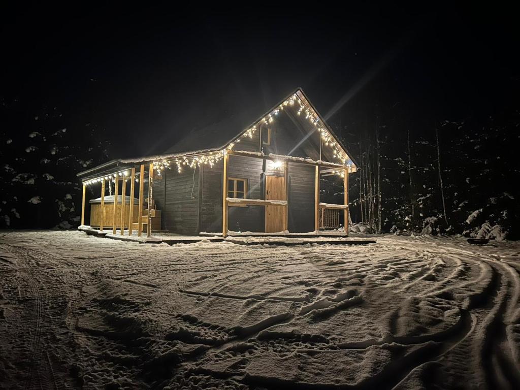 a house with lights on it in the snow at Activfarm domki na Kaszubach /domek Madzia in Lipnica