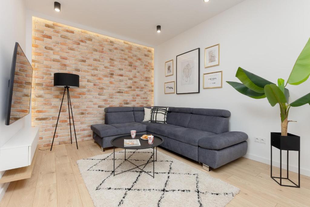 a living room with a blue couch and a brick wall at Loft Apartment with Parking in Warsaw by Renters in Warsaw