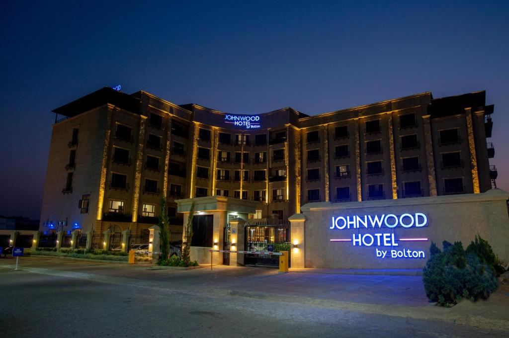 a hotel with a sign on top of it at night at JOHNWOOD HOTEL by Bolton in Wuse