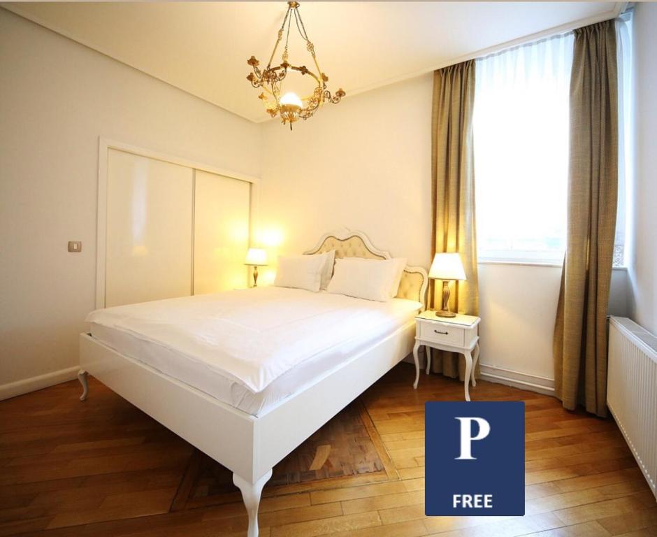 a bedroom with a large white bed with a chandelier at ApartHotel Vila Minka in Ljubljana