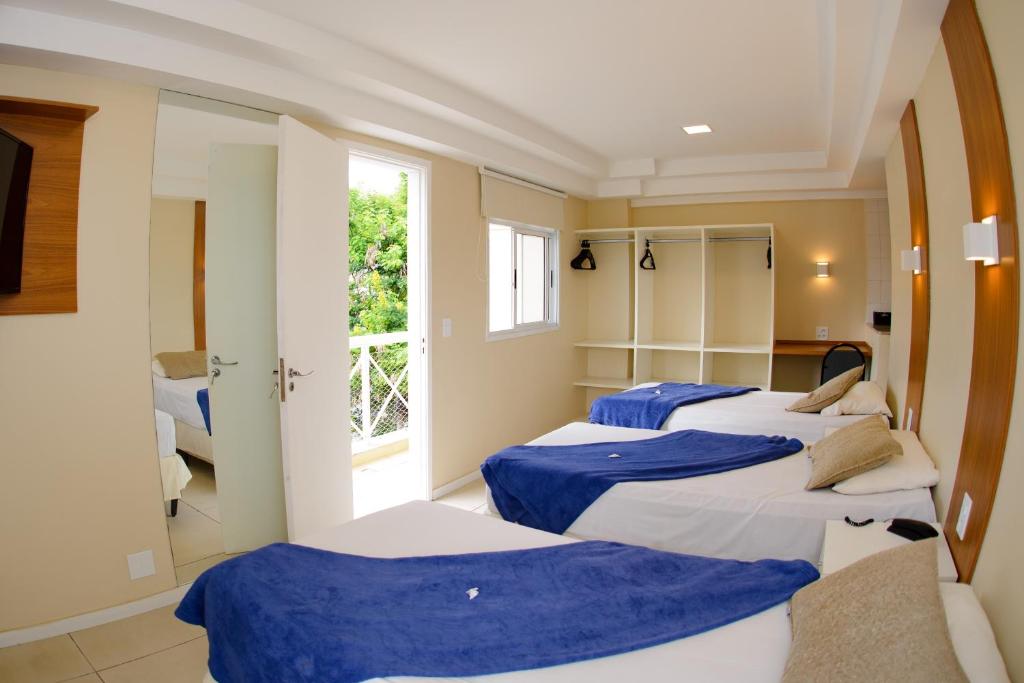 three beds in a room with a window at Hotel Cantareira in Niterói