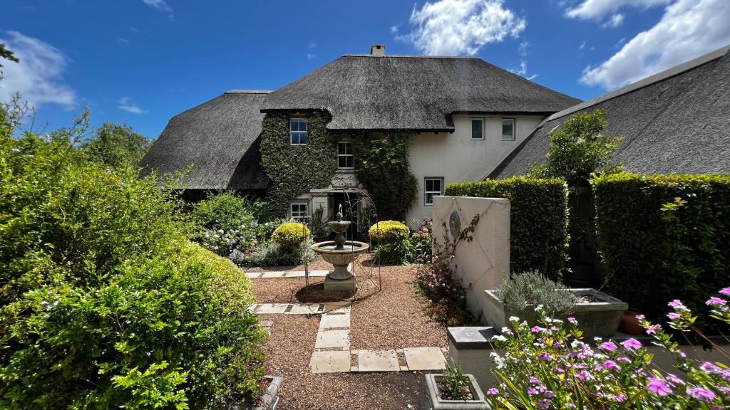 une maison avec un toit de chaume et un jardin dans l'établissement In the Vine Country Manor & Spa, à Stellenbosch