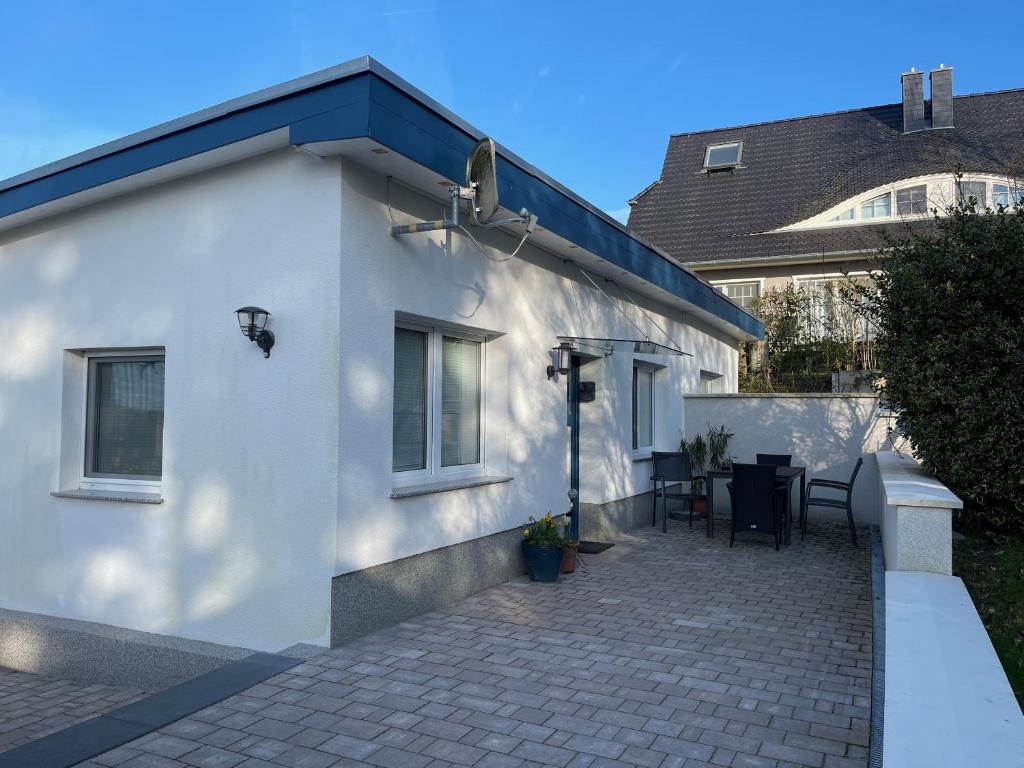 Cette maison blanche dispose d'une terrasse avec une table. dans l'établissement Ruhige Ferienwohnung mit Sonnenterrasse und Garten, à Binz