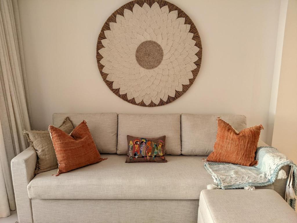 a couch with pillows and a mirror on the wall at Seaview serenity apartment in Flic-en-Flac