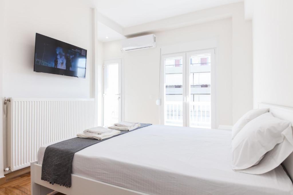 a white bedroom with a bed and a tv on the wall at Stylish New Paradise Apt for 2 in Marousi in Athens