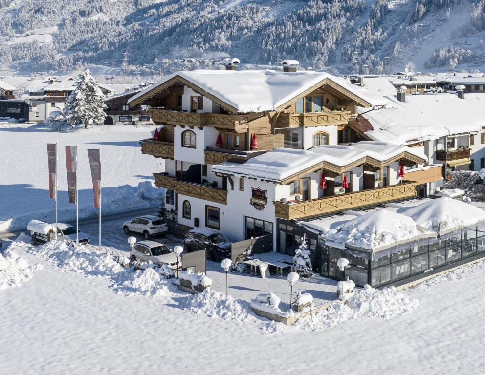 duży drewniany dom w śniegu z śniegiem w obiekcie Hotel Restaurant Rosengarten w mieście Zell am Ziller