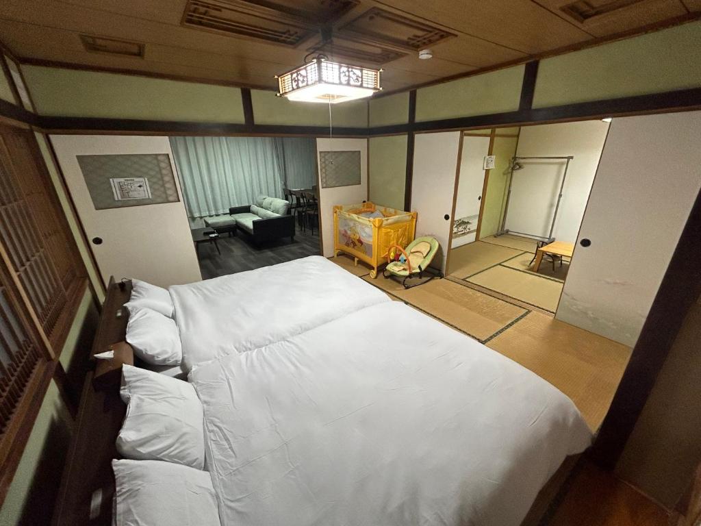 a bedroom with a large bed and a living room at やすらぎの宿 菜の香 in Biei