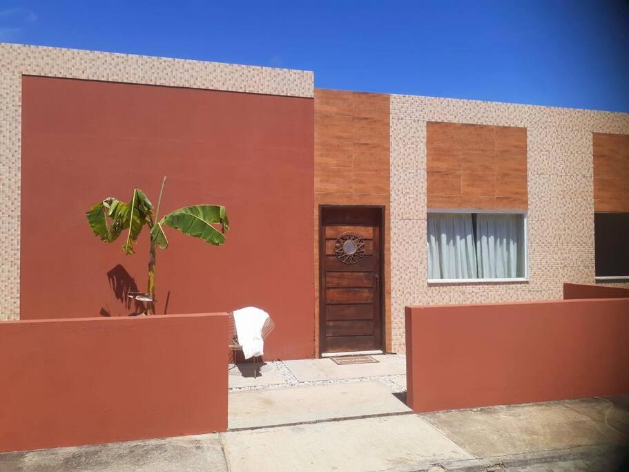 un edificio con una puerta y una planta delante en Linda casa em pequeno condominio! Disponível curtas medias e longas temporadas, en Aracaju