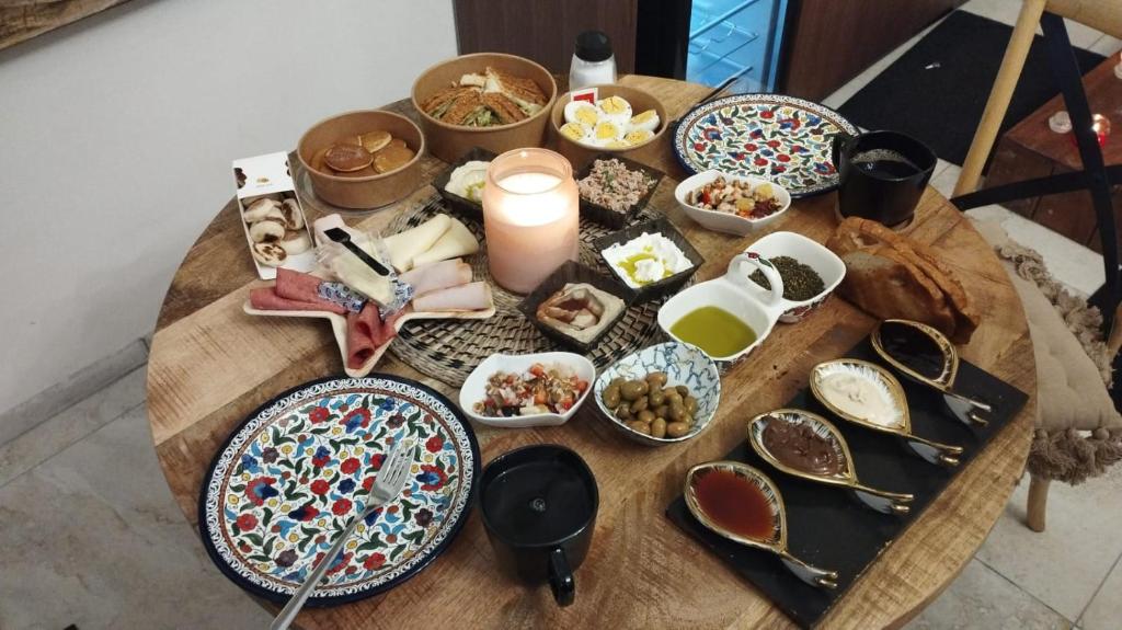 uma mesa com pratos de comida e uma vela em Templars suite em Acre