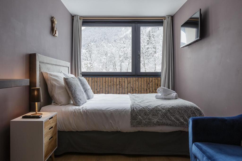 a bedroom with a bed and a large window at Beautiful mountain view studio by the lake in Chamonix-Mont-Blanc