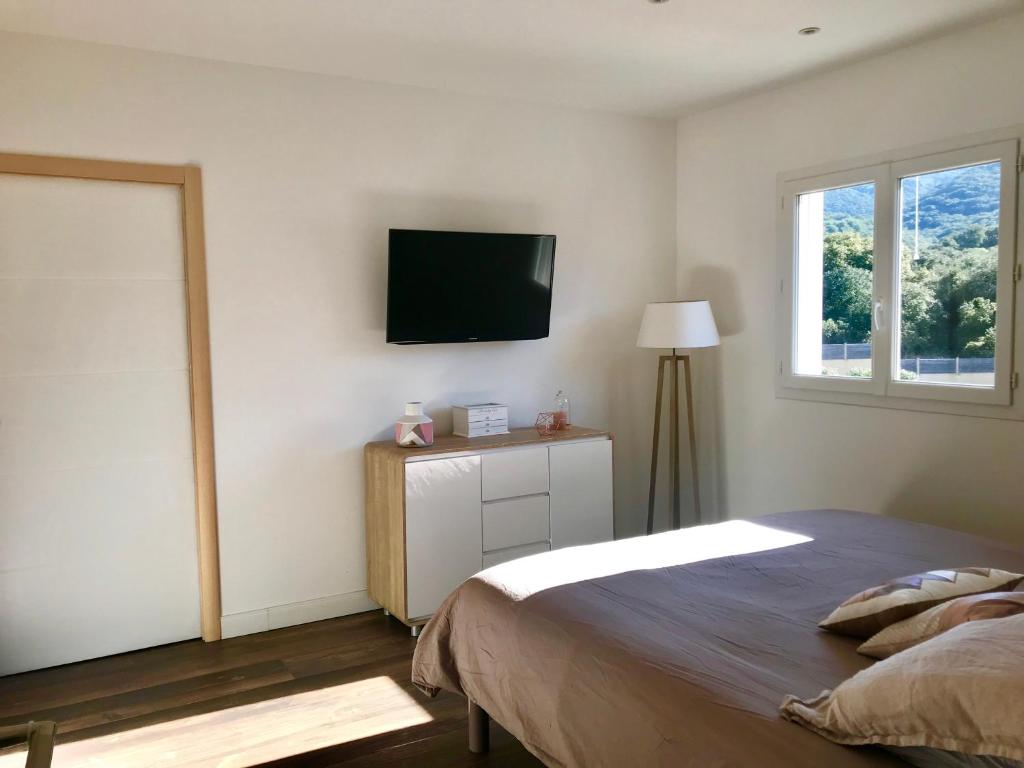 ein Schlafzimmer mit einem Bett und einem TV an der Wand in der Unterkunft Appartement au calme in Propriano