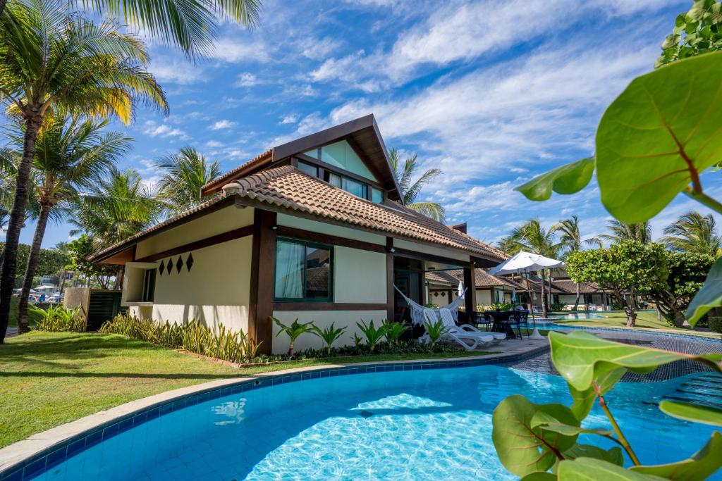 a villa with a swimming pool in front of a house at Bangalô c/ Piscina - Marulhos Resort, Beira Mar de Muro Alto / Porto de Galinhas in Porto De Galinhas