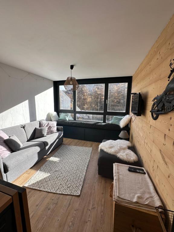 uma sala de estar com um sofá e uma grande janela em SKI AUX PIEDS em Vars