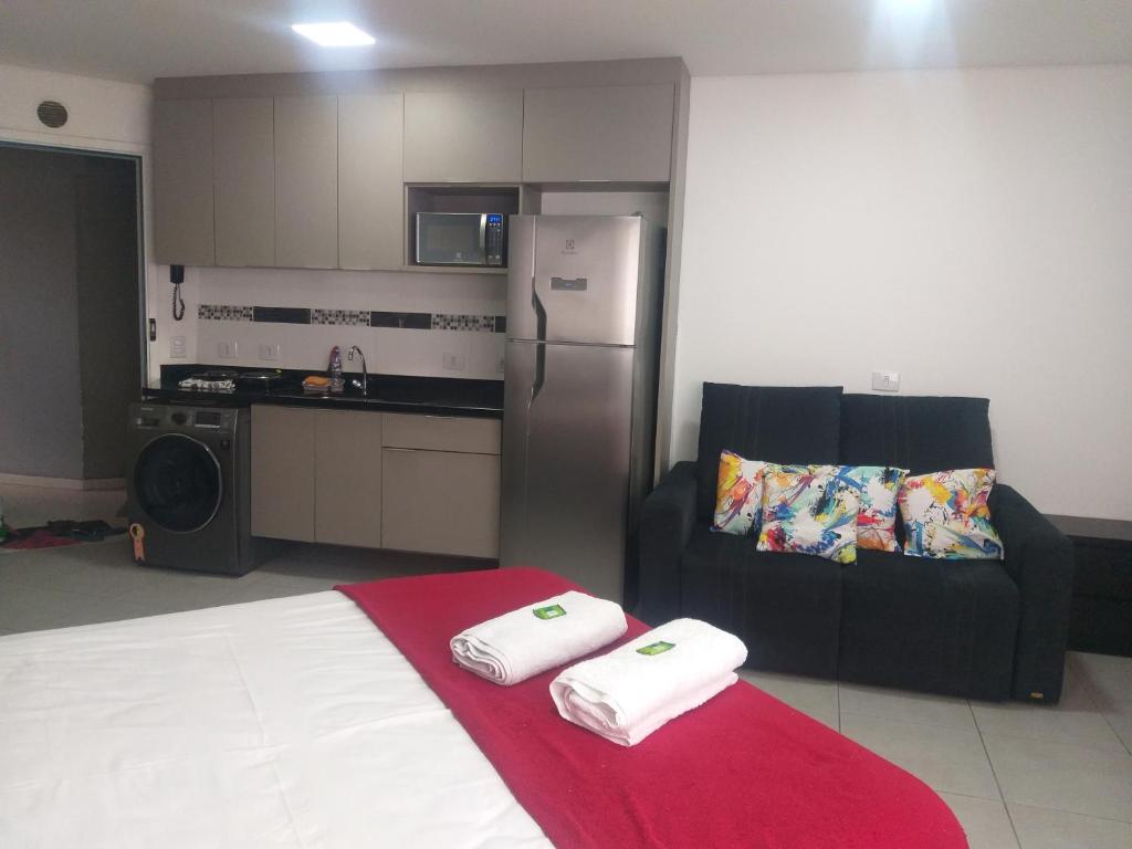 a kitchen with a bed and a refrigerator and a couch at Flat Centro de São Paulo in Sao Paulo