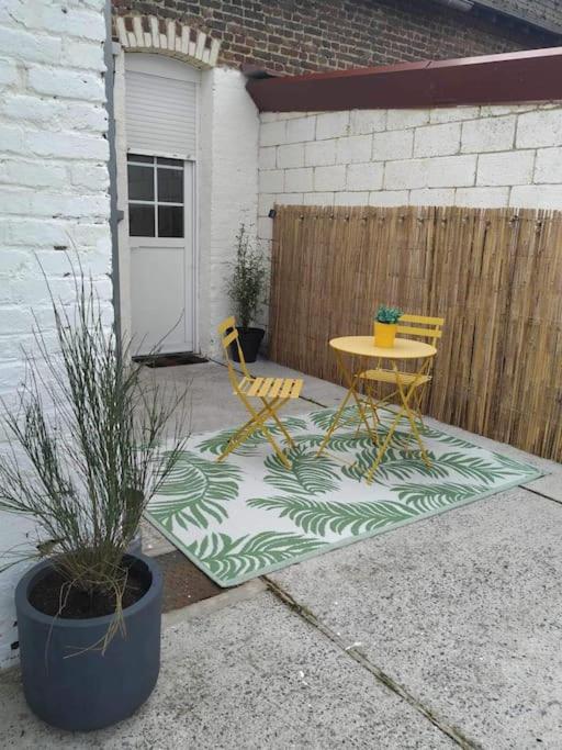 un patio avec une table et des chaises et une clôture dans l'établissement Maison 2 chambres tout équipée, à Vitry-en-Artois