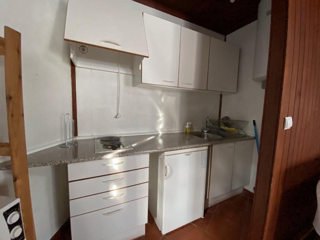 a small kitchen with white cabinets and a sink at YMCA Camp Alambre in Azeitao