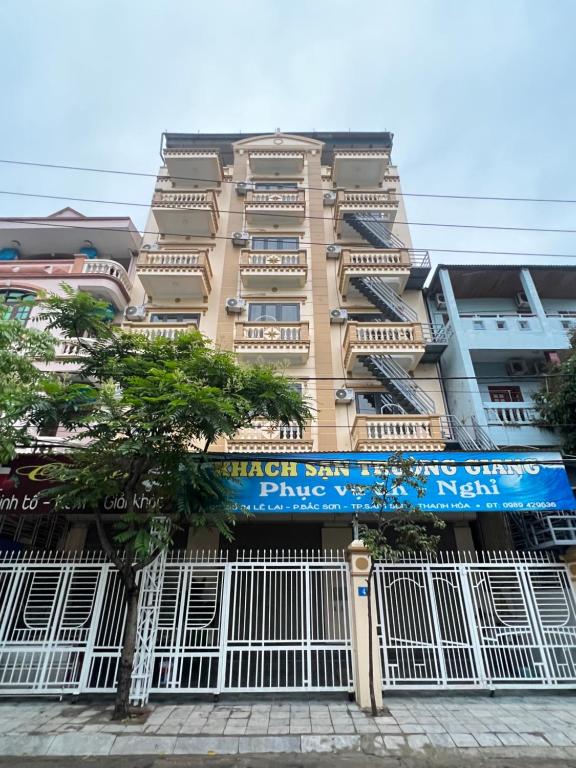 un grand bâtiment avec un panneau bleu devant lui dans l'établissement Khách sạn Trường Giang, à Thanh Hóa