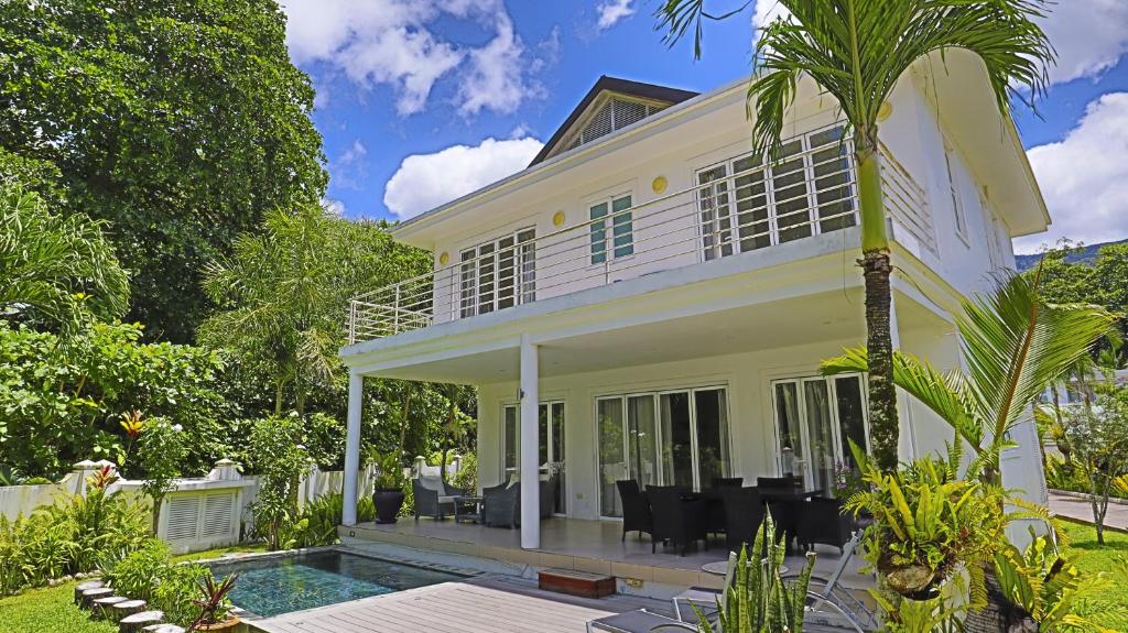 a white house with a pool and a palm tree at Villa Blanc in Beau Vallon