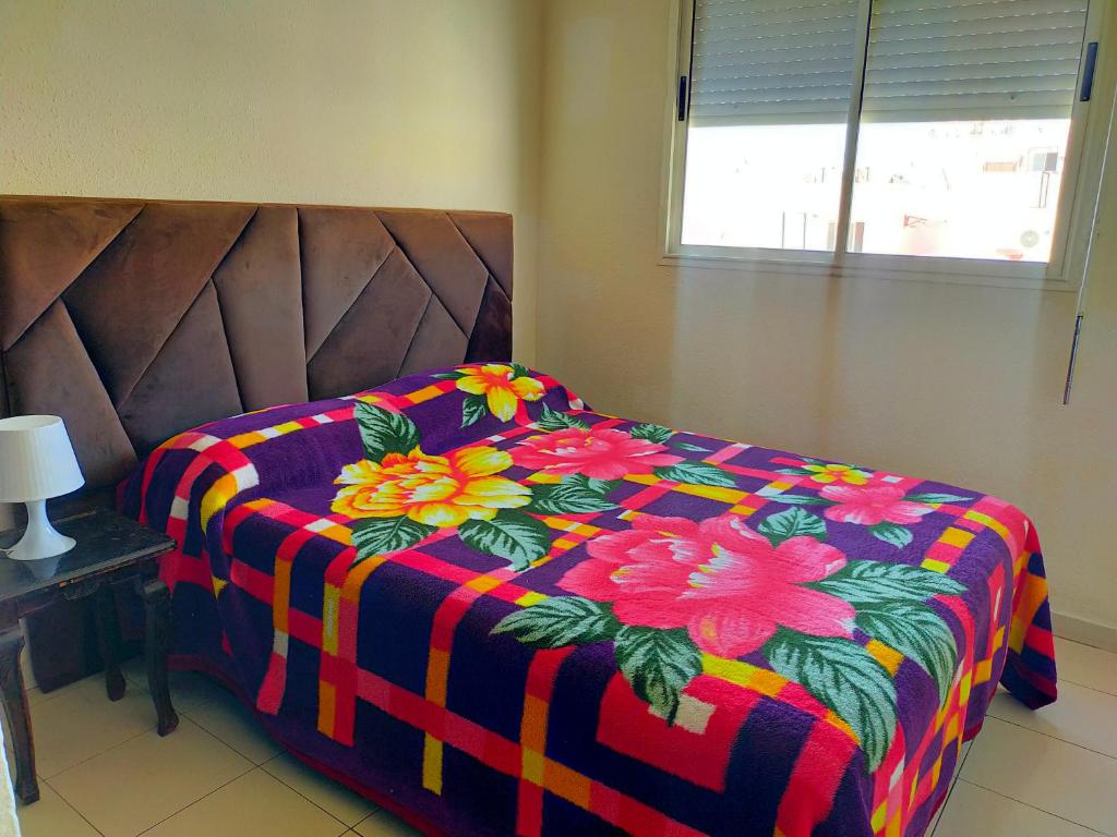 - un lit avec une couverture colorée et des fleurs dans l'établissement Begoniâ house, à Agadir