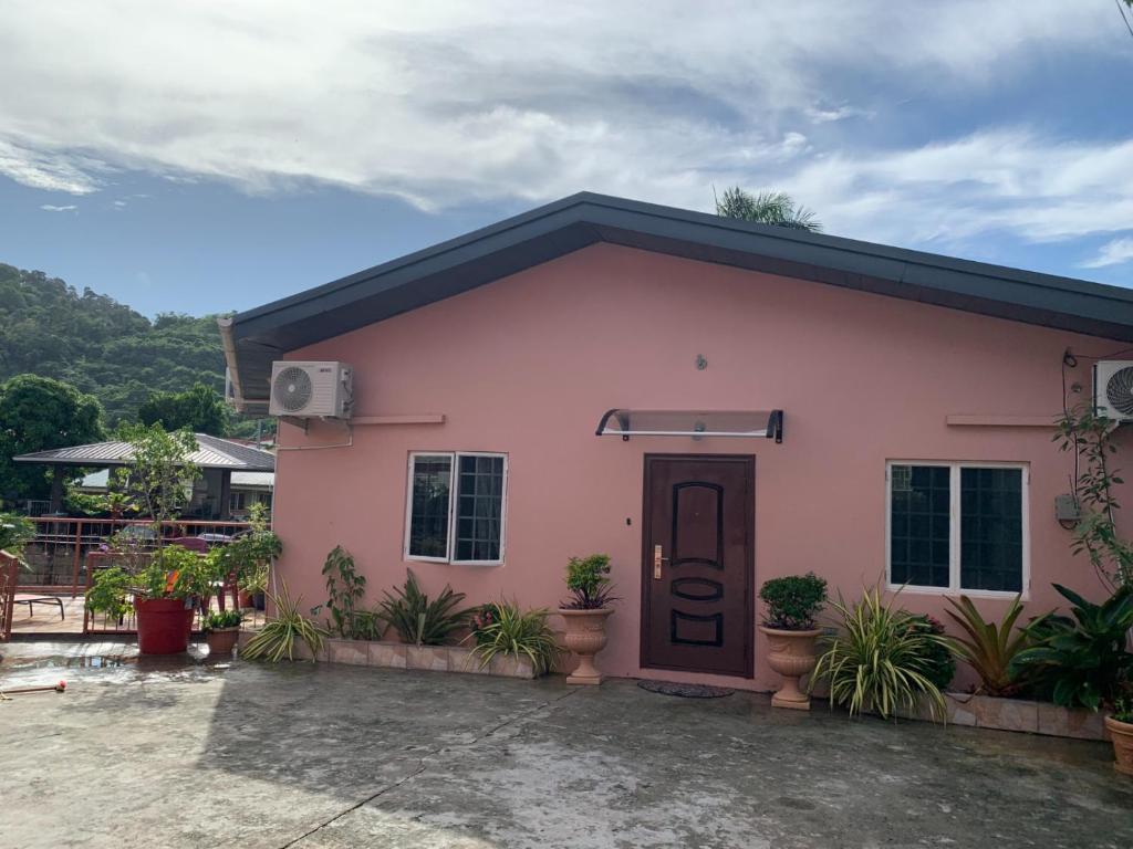 a pink house with plants in front of it at Quiet 2-bed property within the centre of city in Port-of-Spain