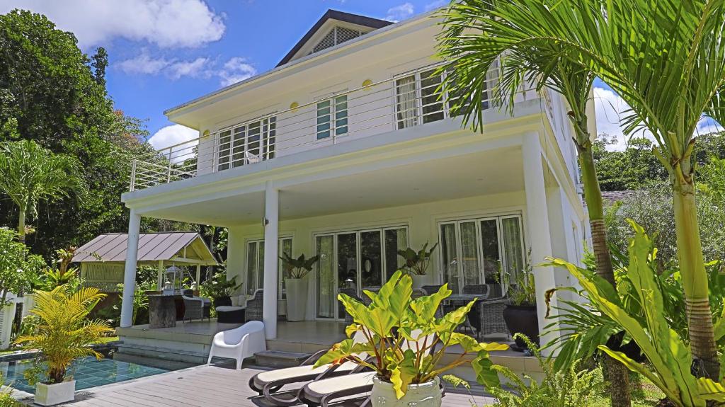 a white house with a pool and palm trees at Les Jolies Eaux Villa - Chateau Elysium in Beau Vallon