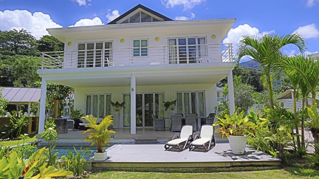 a white house with chairs in front of it at Les Jolies Eaux Villa - Chateau Elysium in Beau Vallon