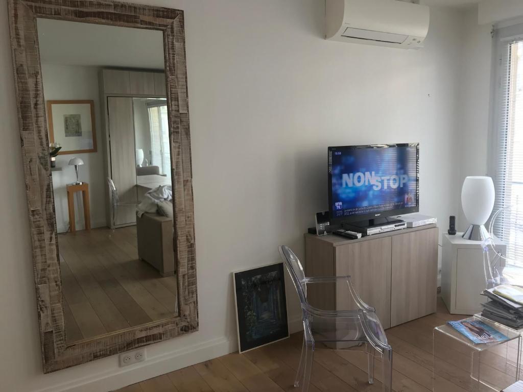 d'un salon avec un miroir, une télévision et une chaise. dans l'établissement TROCADERO-TOUR EIFFEL-Champs Elysees, à Paris