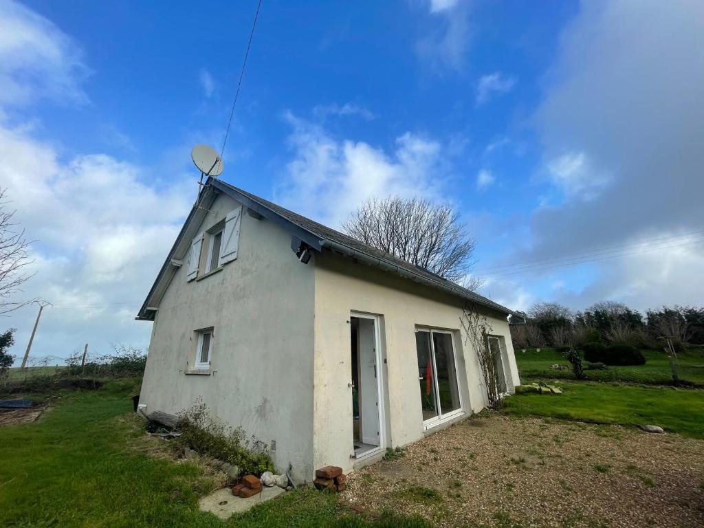une petite maison blanche sur une pelouse dans l'établissement La cote Normande, à Saint-Martin-aux-Buneaux