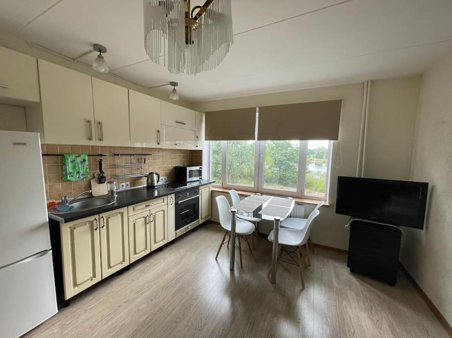 a kitchen with a table and white chairs in it at Cozy Family River View Flat Near The Beach Seaside in Rīga