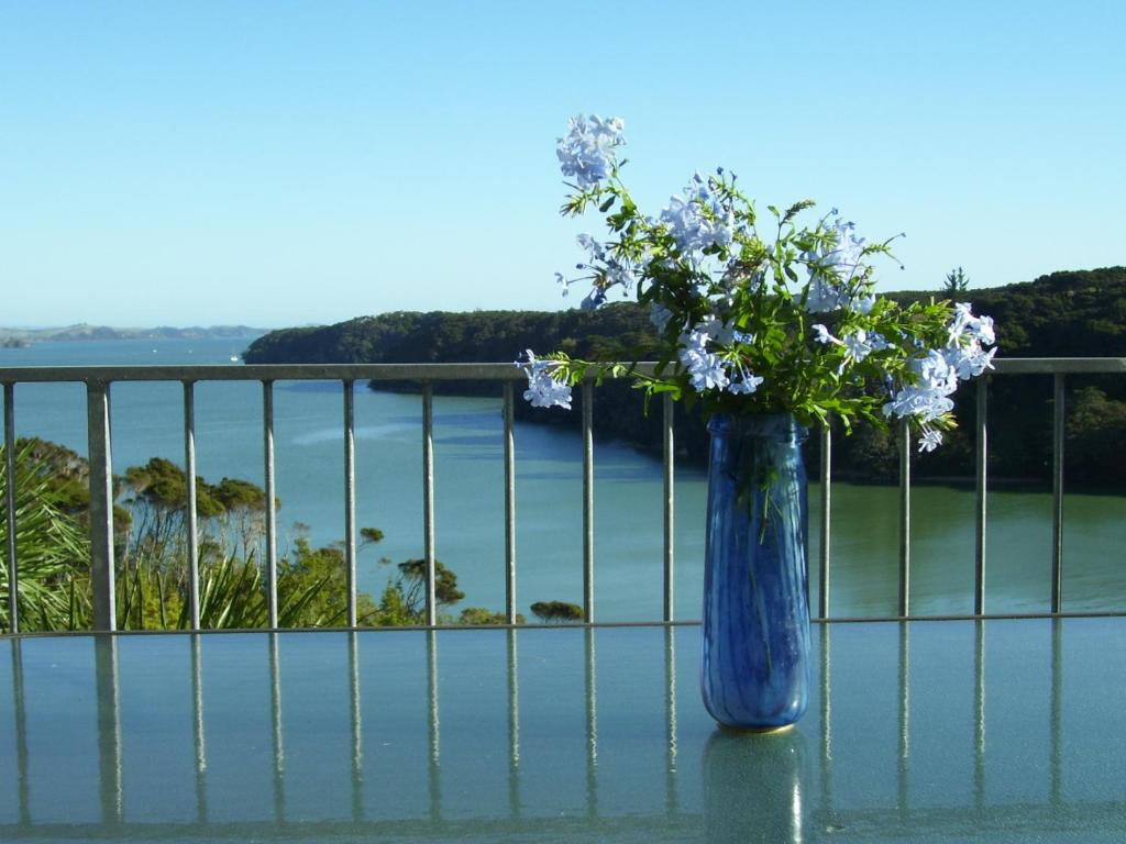 un vaso blu pieno di fiori seduto su un tavolo di Pipiroa Bay Homestay a Russell