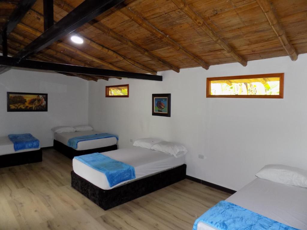 two beds in a room with white walls and wooden ceilings at Finca La Esperanza Pereira in Pereira