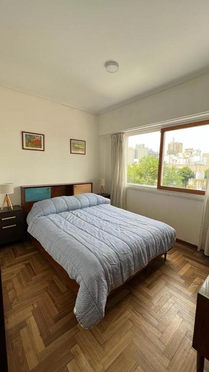 ein Schlafzimmer mit einem Bett und einem großen Fenster in der Unterkunft Check and Home - Rawson - 4 huéspedes amplio en el centro in Mar del Plata