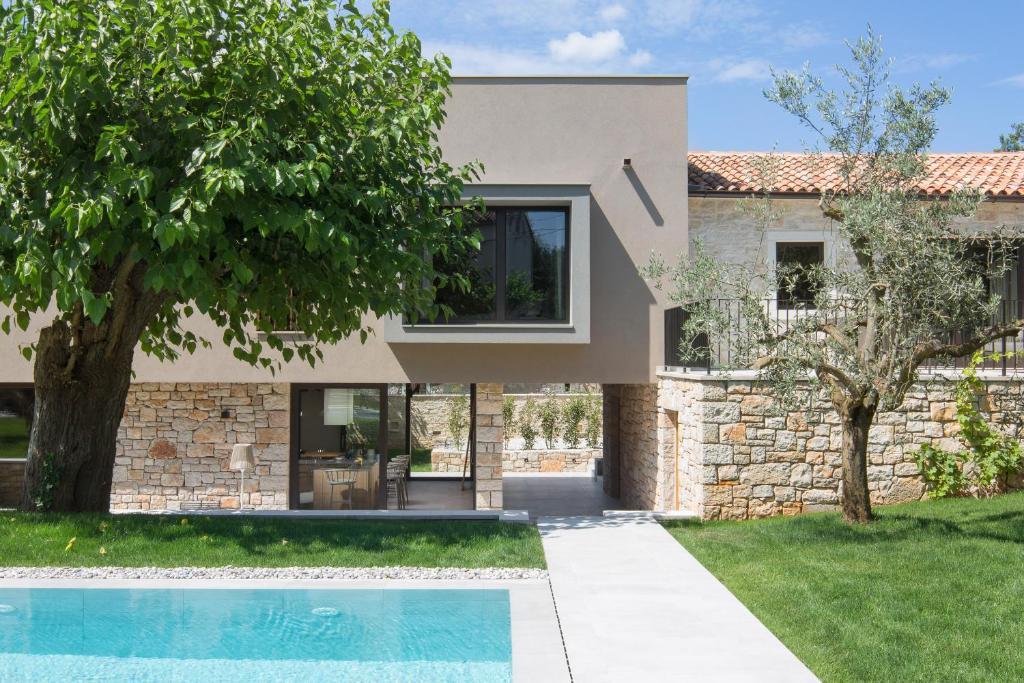 a house with a swimming pool and a stone wall at Modern Villa Melon with outdoor pool in Porec in Krmenjak