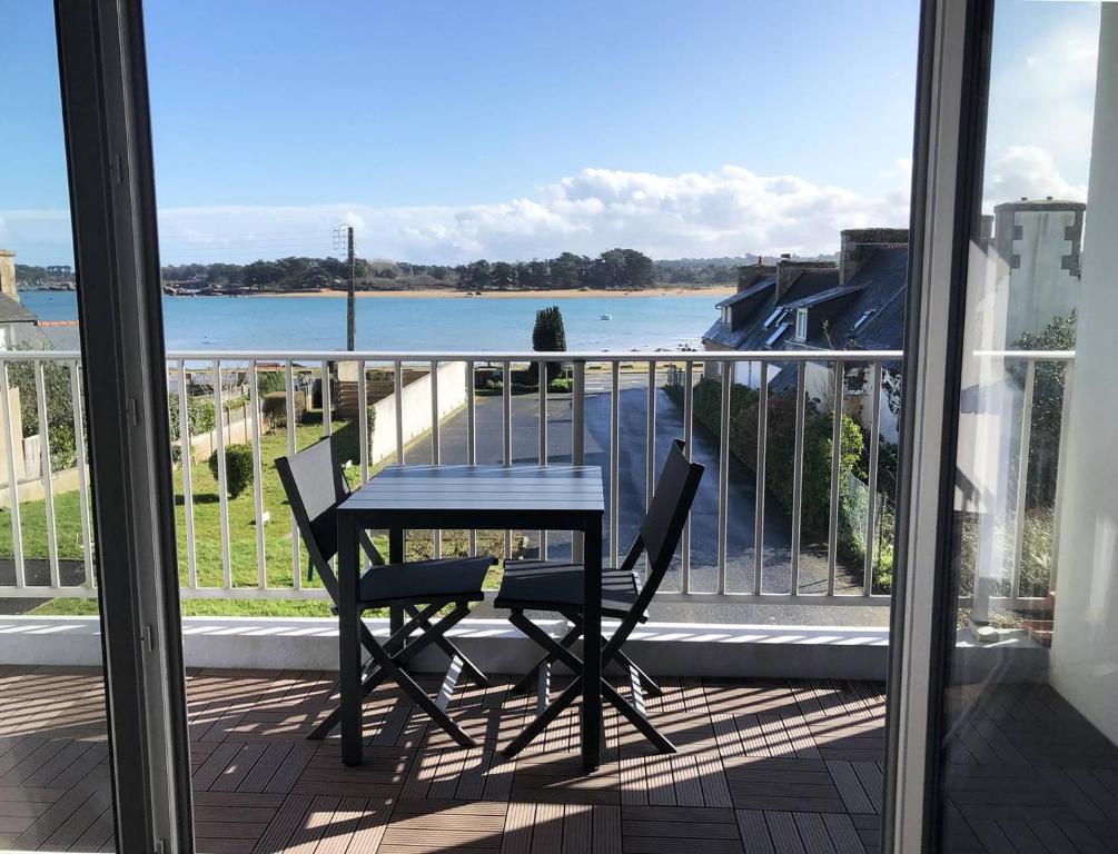 une table et des chaises sur un balcon avec vue sur l'eau dans l'établissement Appartement SUPERBE VUE MER avec balcon, WIFI, à TREGASTEL - Réf 93, à Trégastel