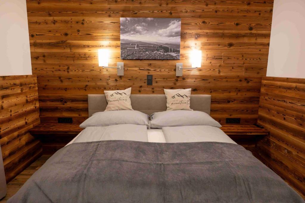 Cama grande en habitación con paredes de madera en Pension Kreischberg Mayer, en Sankt Lorenzen ob Murau