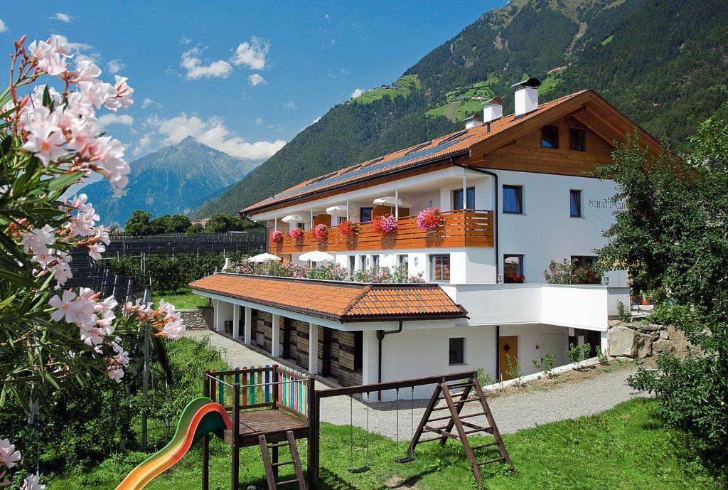 a building with a playground in front of a mountain at Schattmair Hof in Tirolo